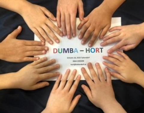 Kinderhände um das Schild Dumba-Hort